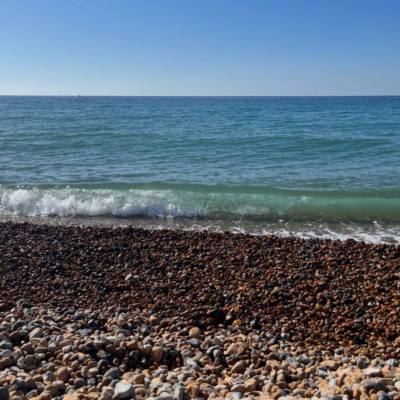 Glassy green water catching the sun on Brighton beach.