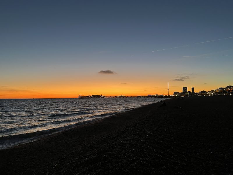 Brighton Pier and the beach silhouetted against a brilliant orange sunset.