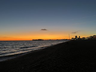 Brighton Pier and the beach silhouetted against a brilliant orange sunset.