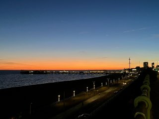 Brighton Pier, the beach and the promenade silhouetted against a brilliant orange sunset.